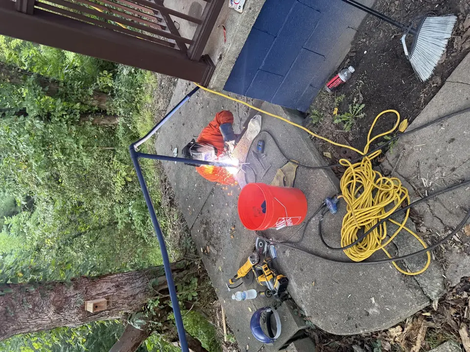 Metal handrail welding repair beside a concrete walkway